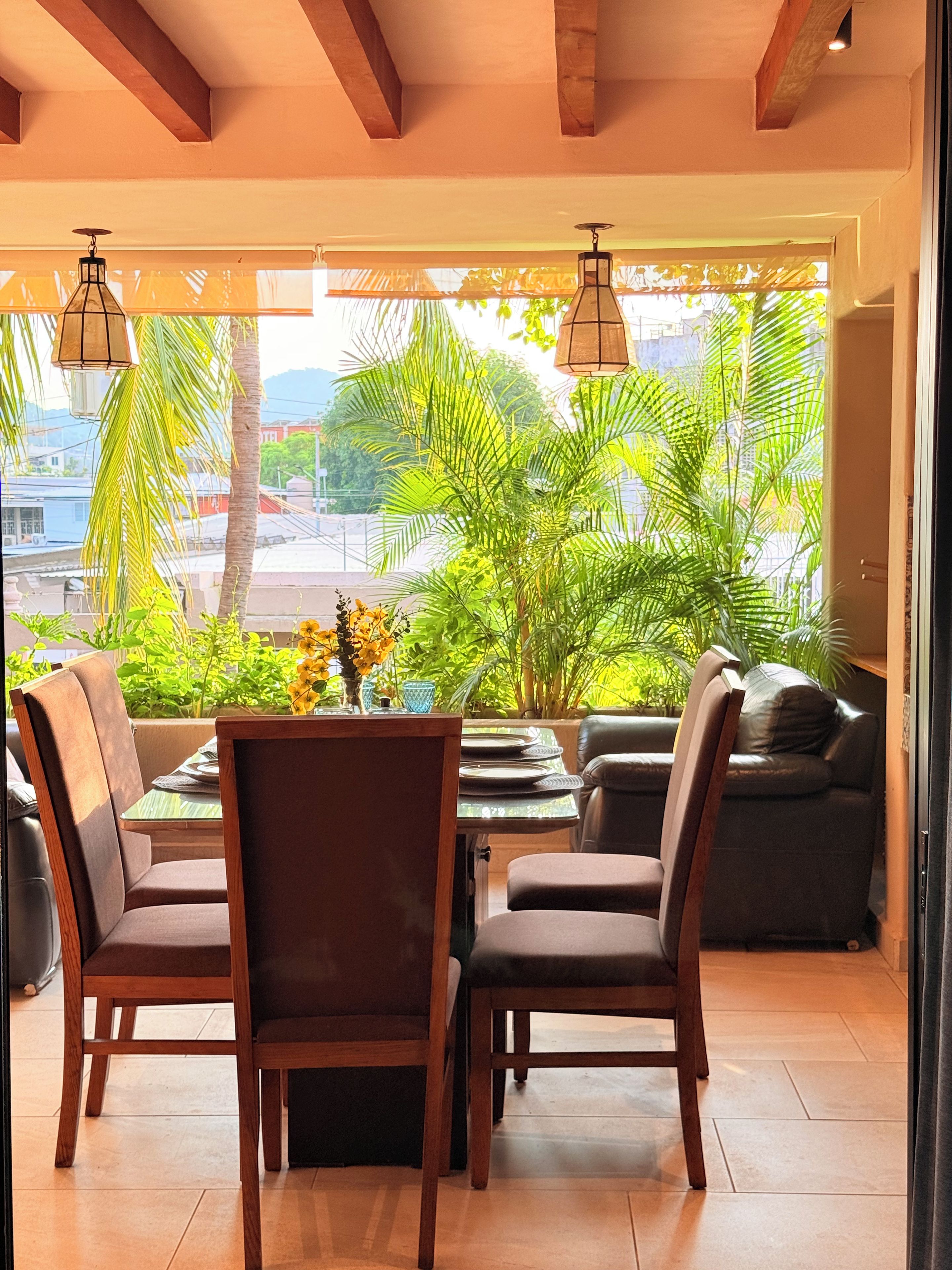 A dining area with a view of palm trees and a cityscape.