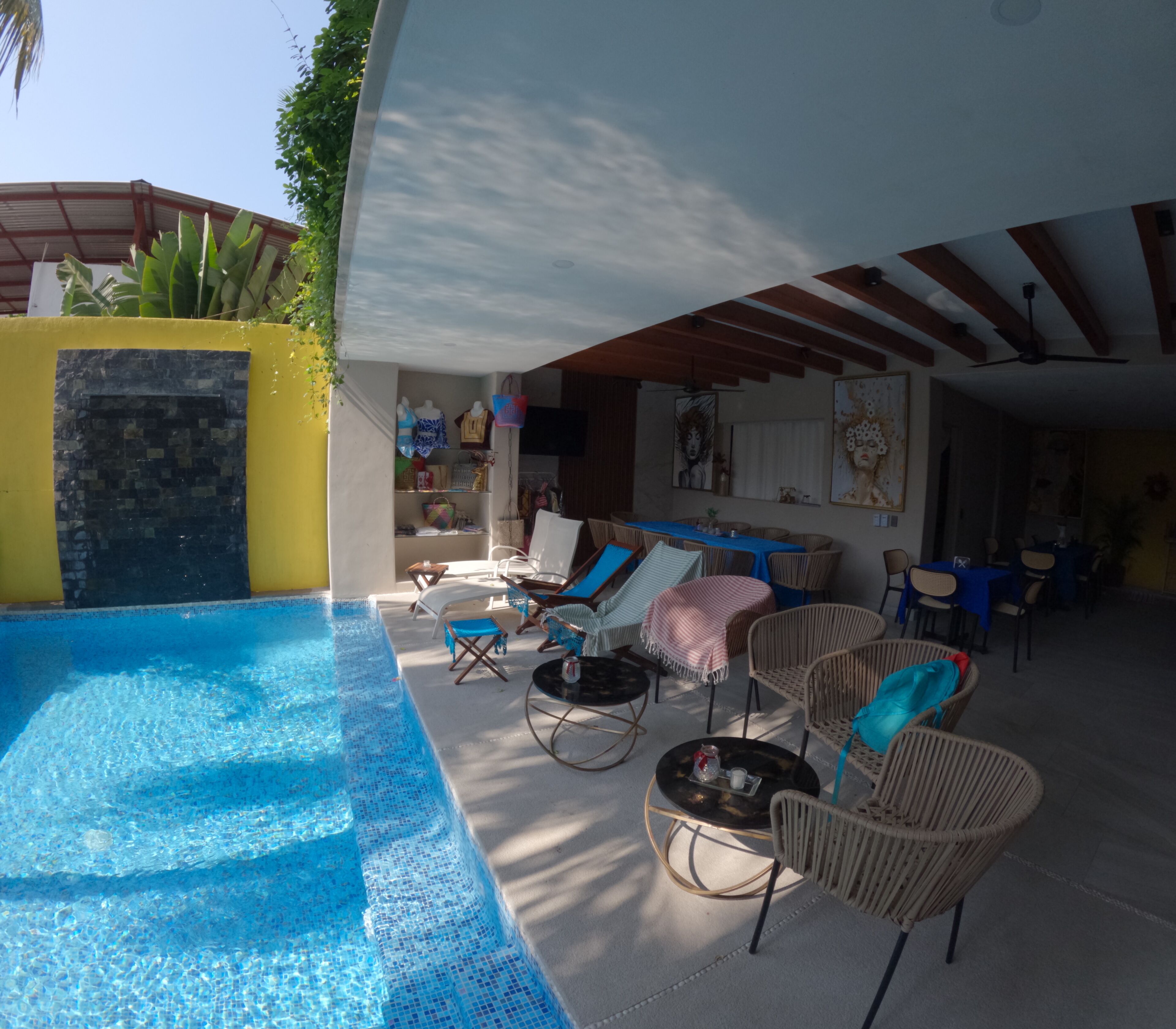 Un espace aménagé au bord de la piscine, avec des chaises longues, une table à manger et un patio couvert.