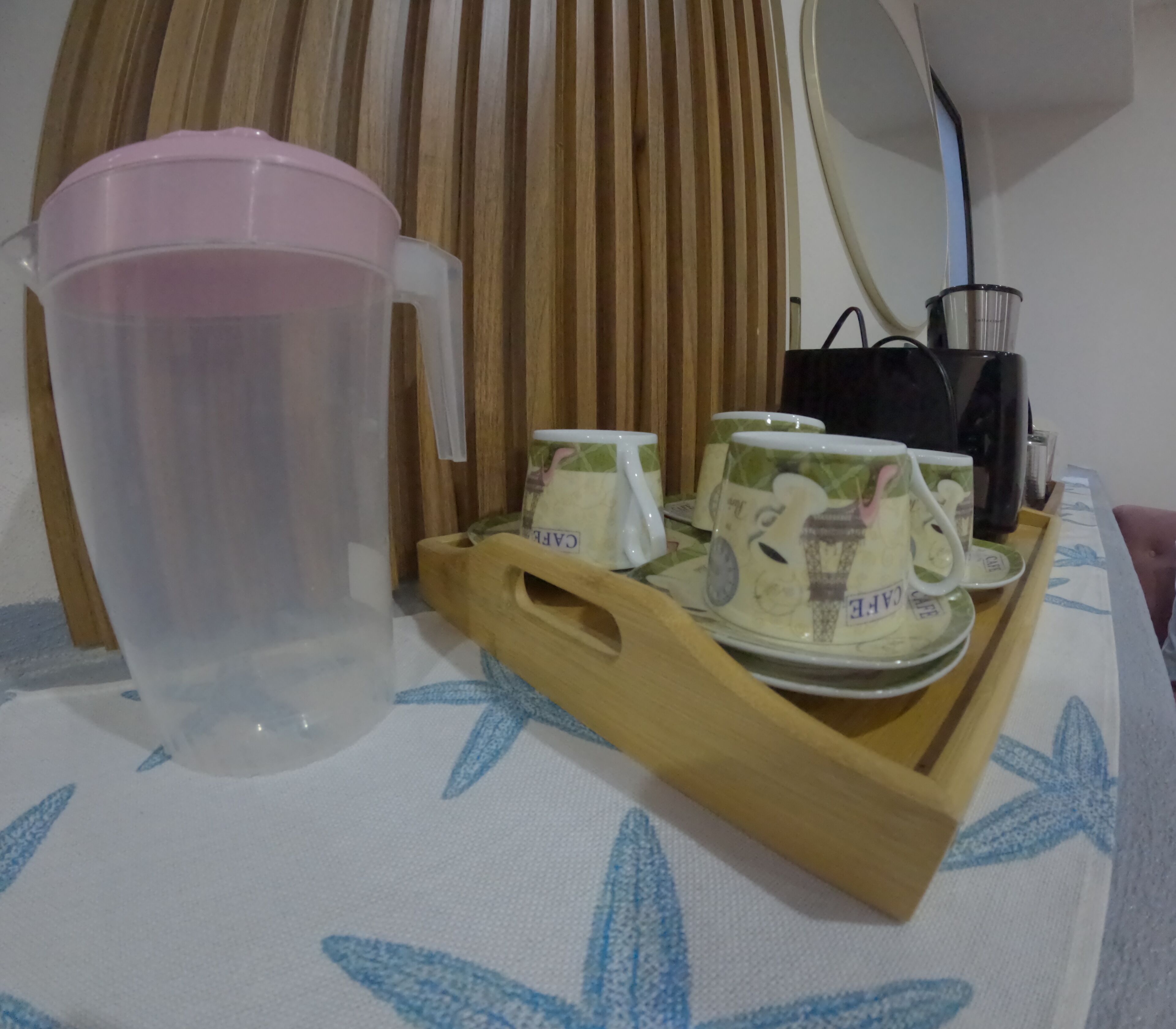 A tray with a pitcher and four cups on a table.
