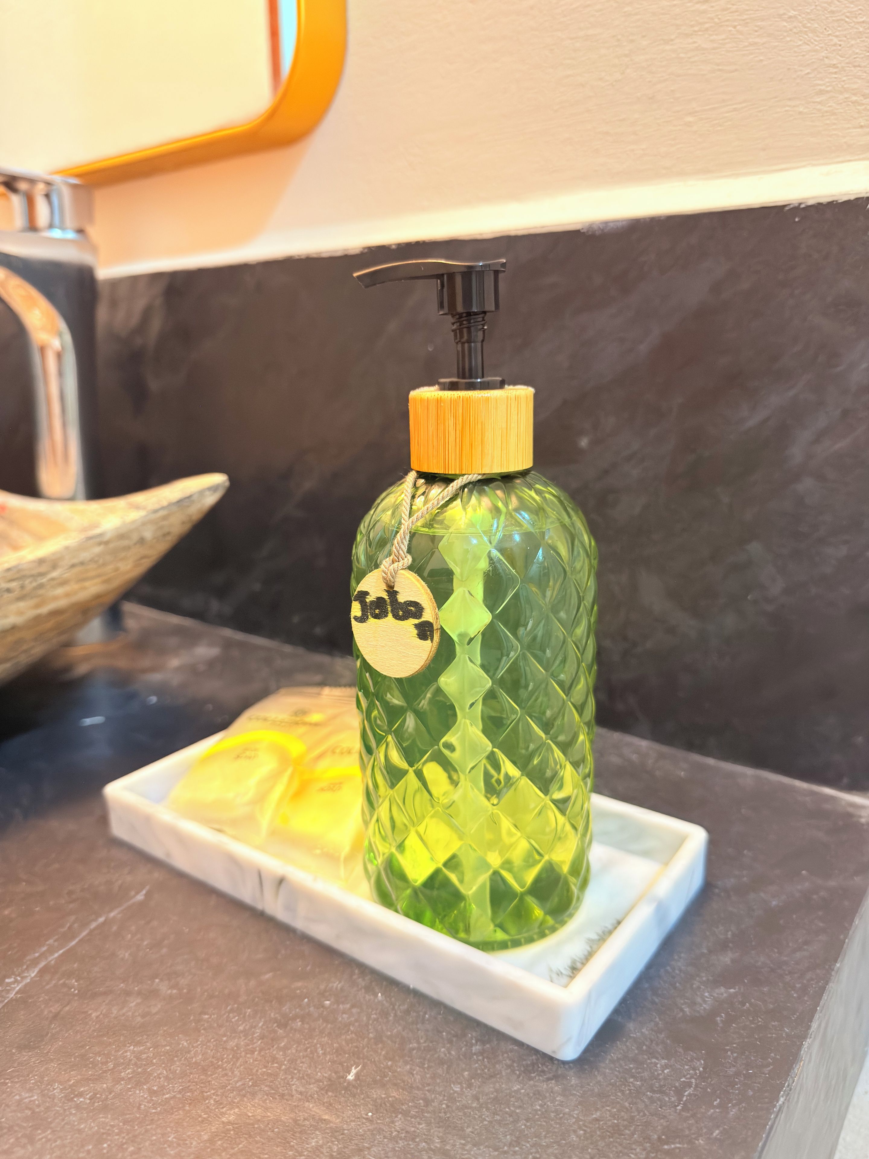 A green bottle with a pump dispenser on a white tray.