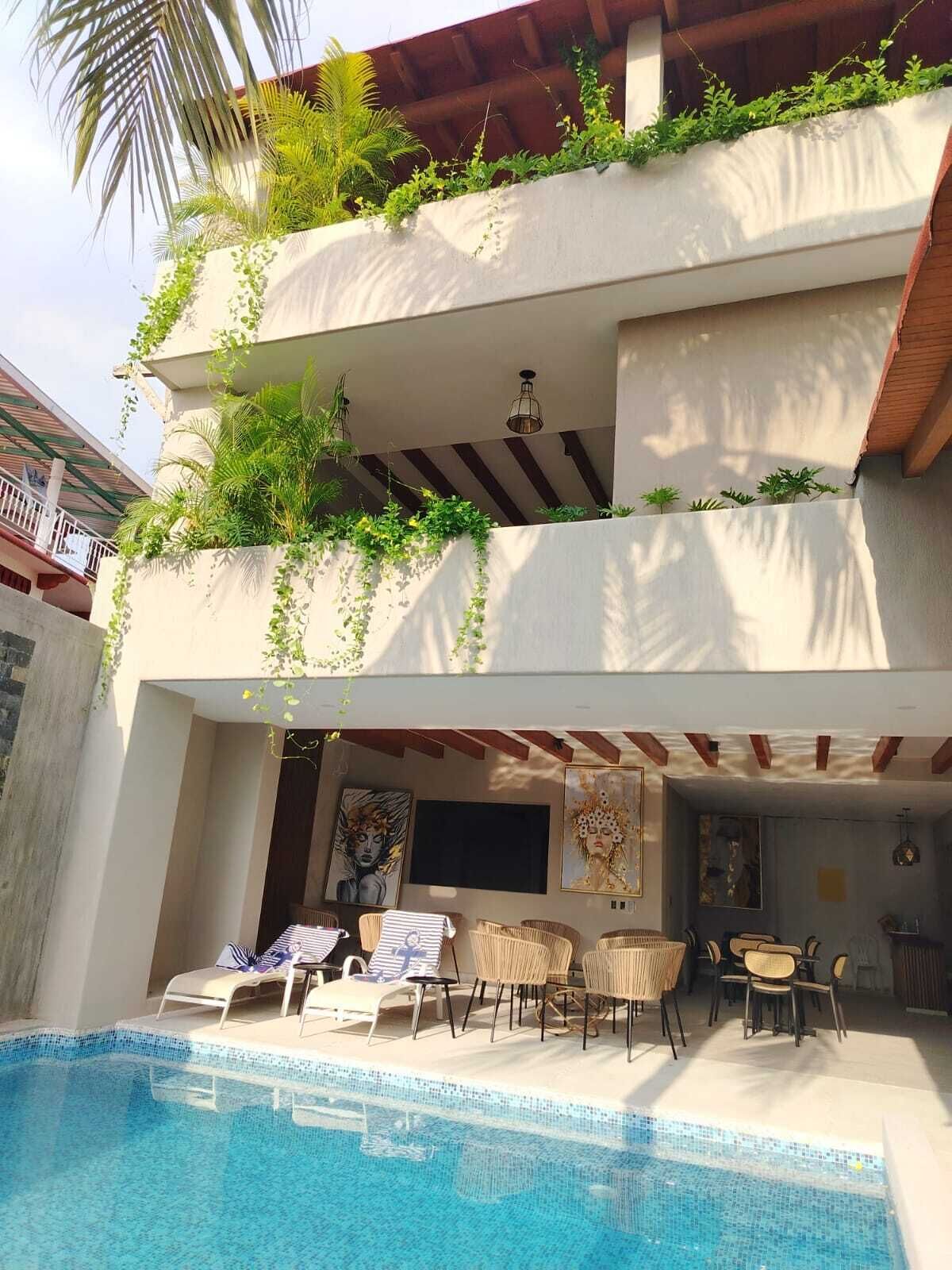 A two-story building with a swimming pool, outdoor seating, and lush greenery.