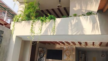 A two-story building with a swimming pool, outdoor seating, and lush greenery.