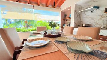 Comedor con una mesa lista para cuatro personas, sillas alrededor y vistas al exterior.