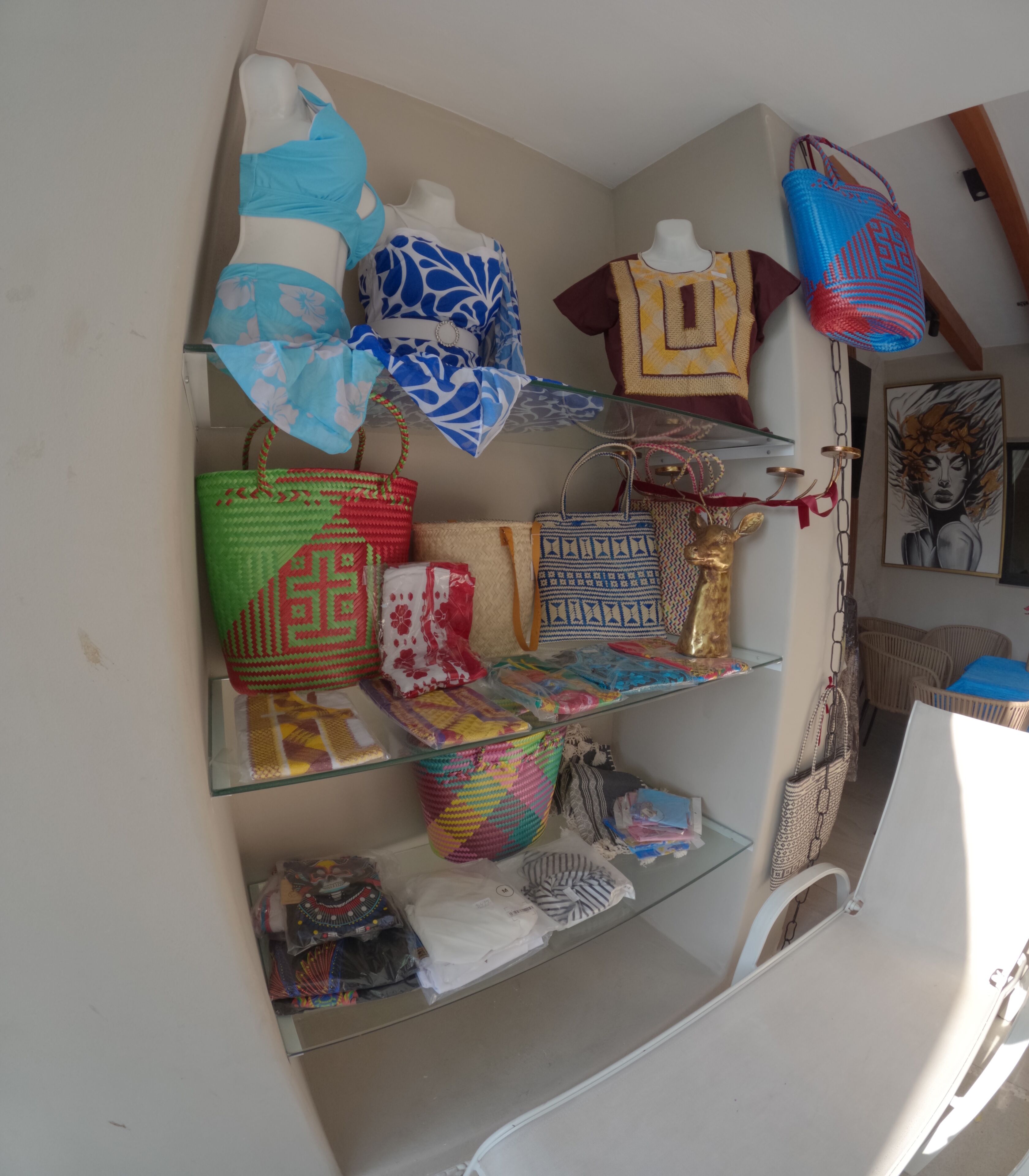Une exposition de différents sacs et accessoires présentés sur des étagères et suspendus au plafond.