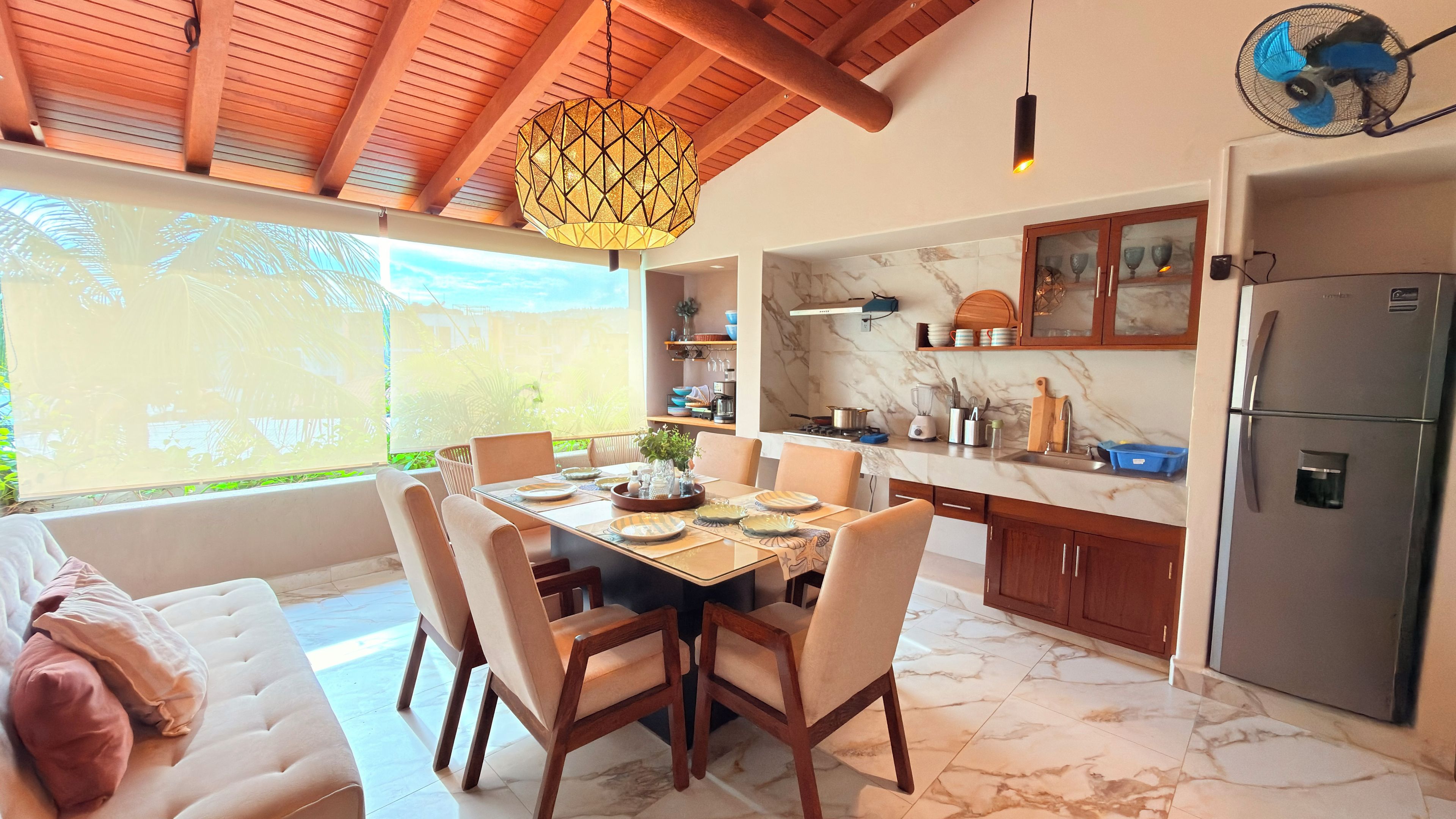 A modern kitchen with marble countertops, wooden cabinets, and a dining area with a table set for four.