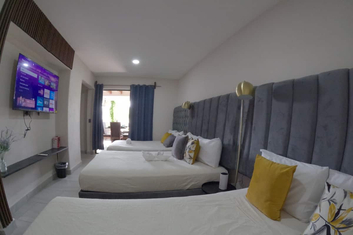 A hotel room with two beds, a flat-screen TV mounted on the wall, a desk with a chair, and a view of the outdoors.