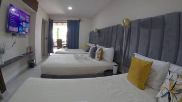 Une chambre d’hôtel avec deux lits, un téléviseur à écran plat fixé au mur, un bureau avec une chaise et une vue sur l’extérieur.