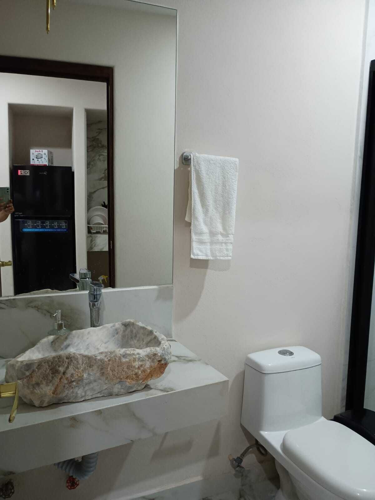 A bathroom with a white sink, a toilet, and a mirror.