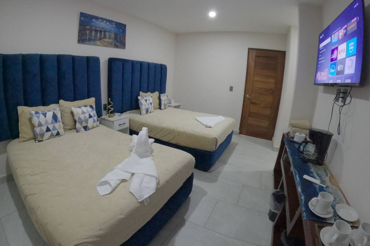 A hotel room with two beds, a TV mounted on the wall, and a wooden door.