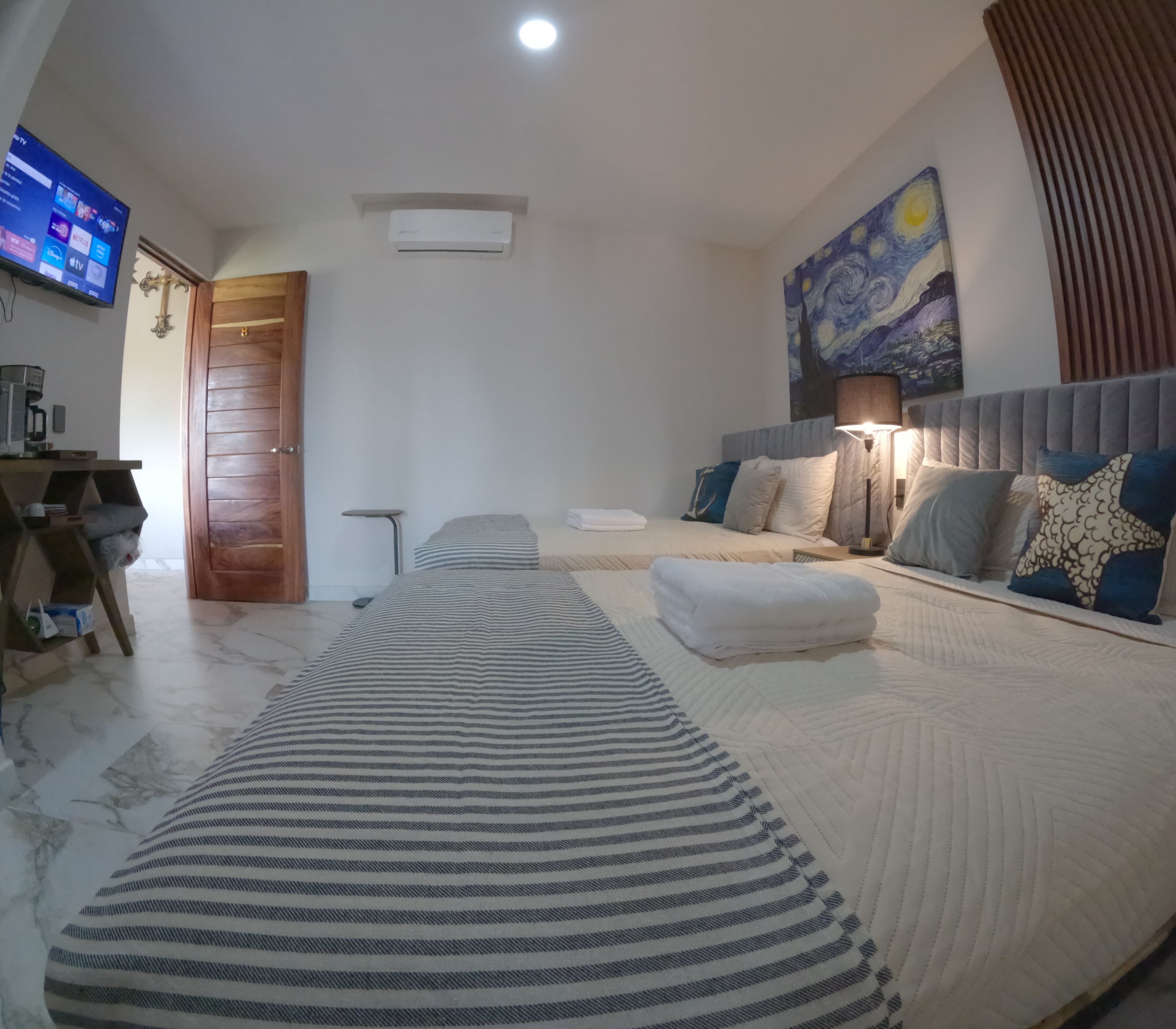A hotel room with a large bed, a flat-screen TV, a coffee machine, and a painting on the wall.