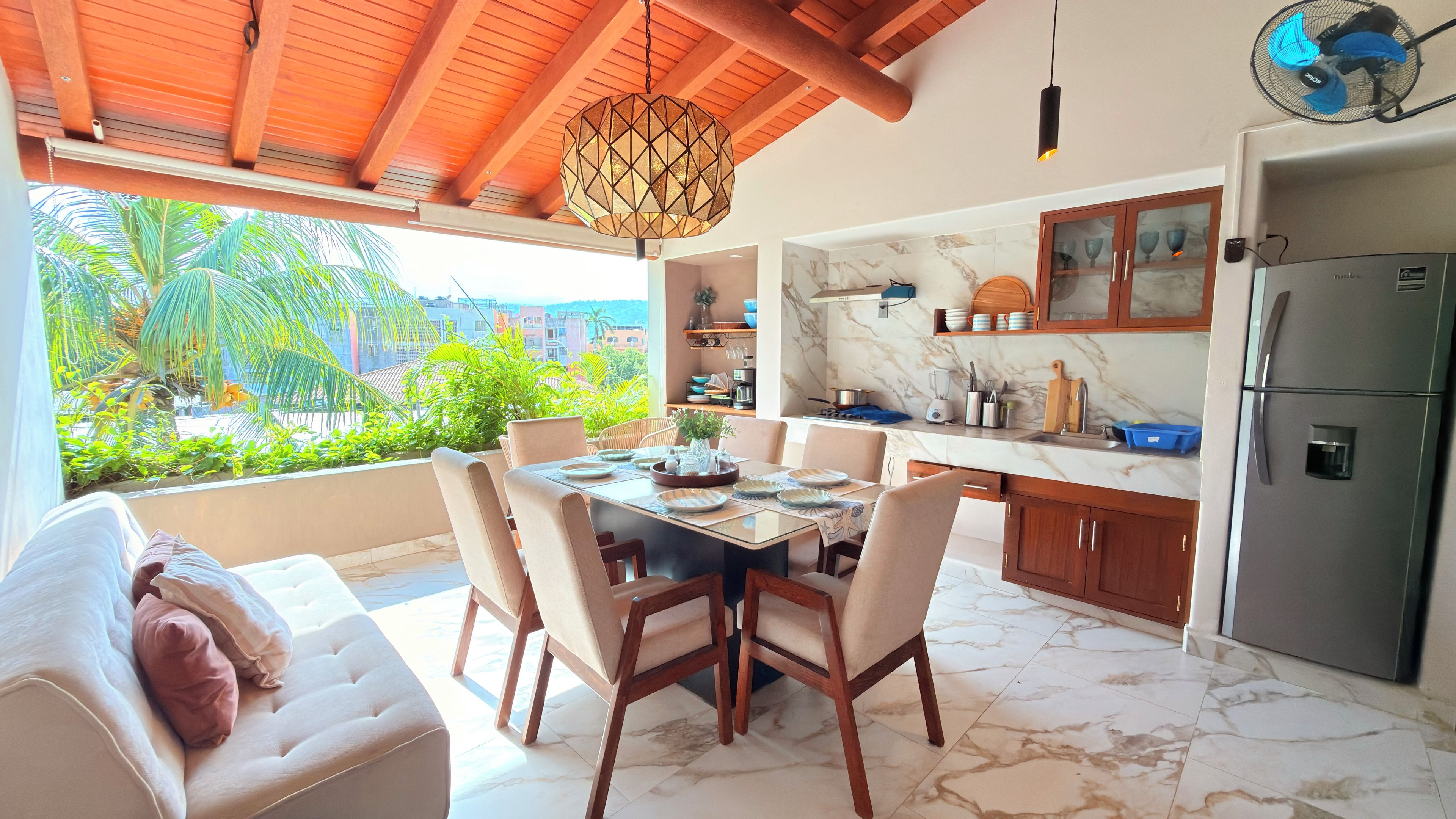 A modern kitchen with marble countertops, a built-in refrigerator, and a dining area with a table set for four.