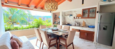 Une cuisine moderne dotée de plans de travail en marbre, d’un réfrigérateur encastré et d’un coin repas avec une table dressée pour quatre personnes.