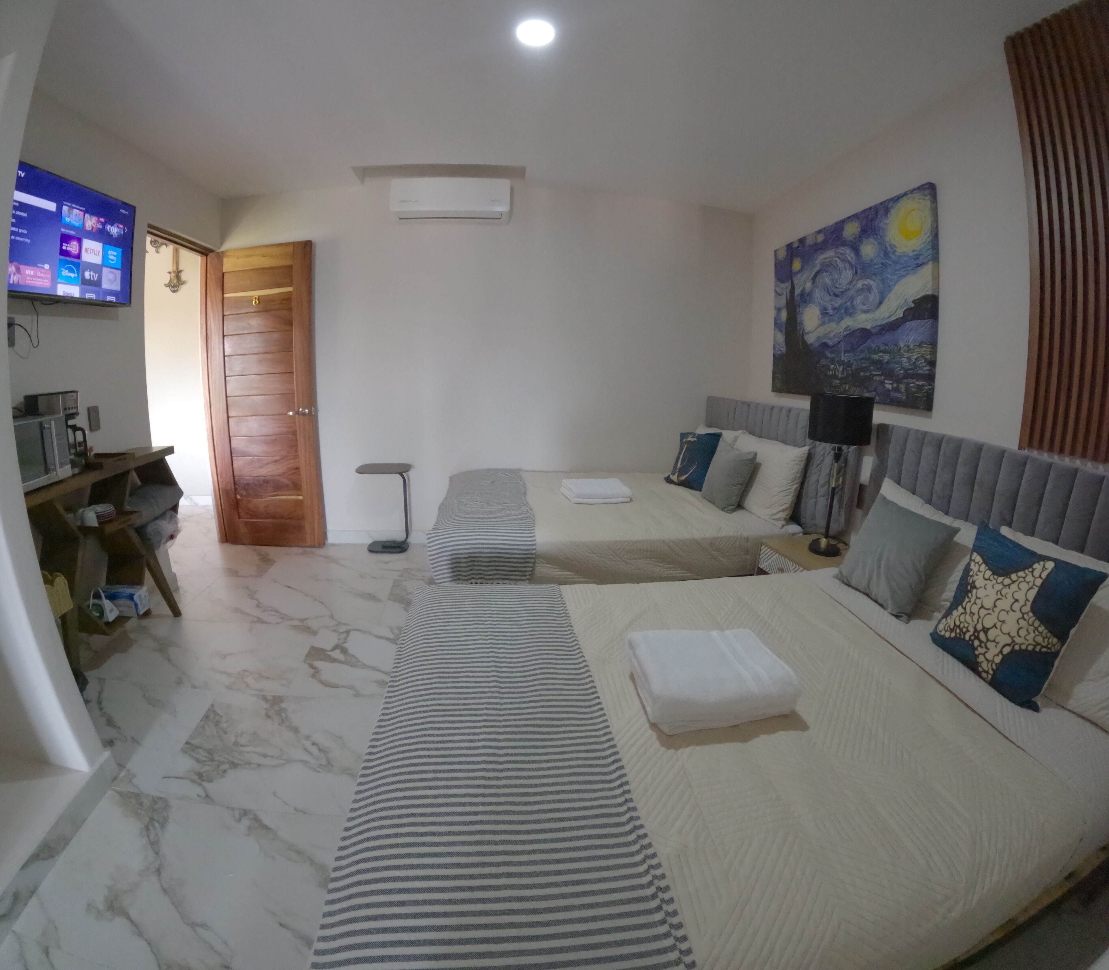 Habitación de hotel con dos camas, un televisor, un escritorio y un cuadro en la pared.
