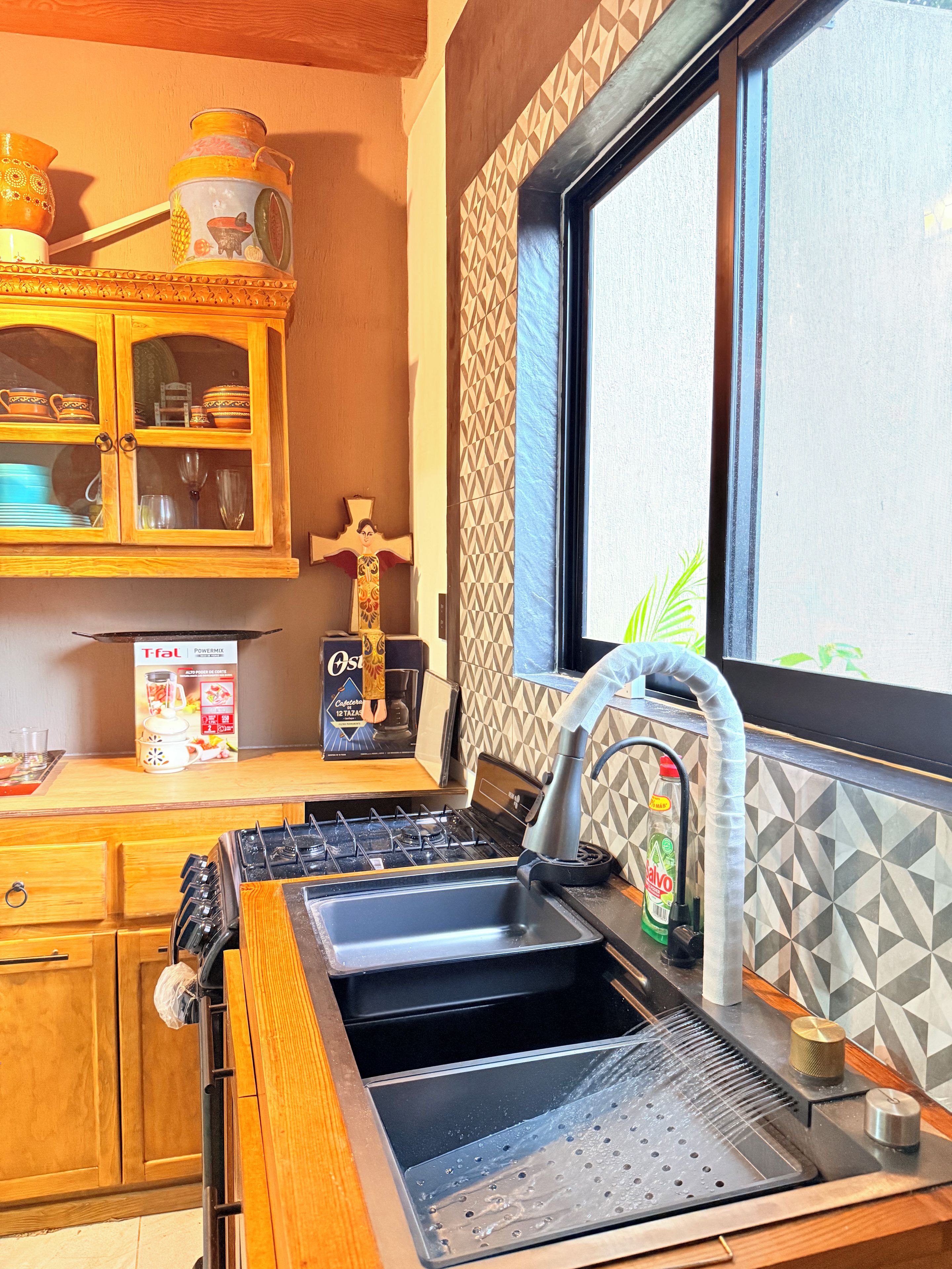 A kitchen with a gas stove, a sink, and a window with a view.