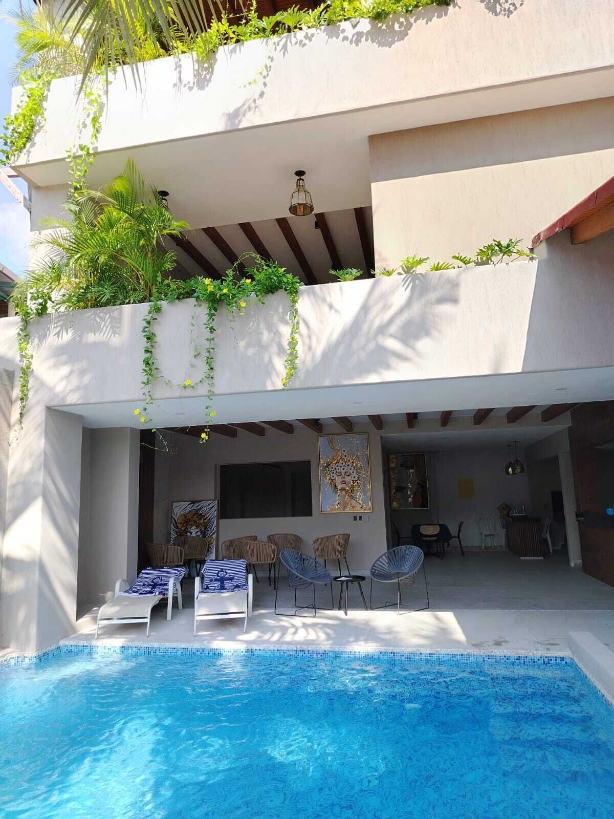 Zona de piscina con sillones reclinables, comedor y vistas a la piscina.