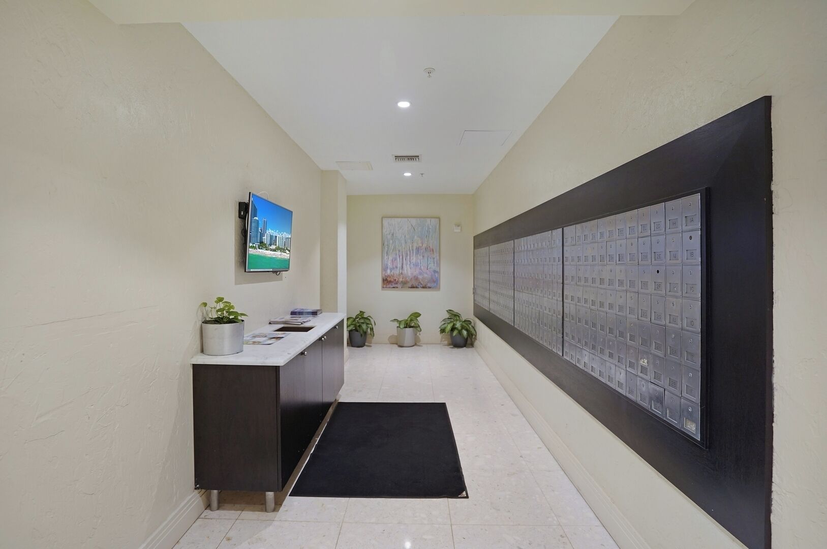 A reception area with a reception desk, a television, a painting, and a wall of mailboxes.