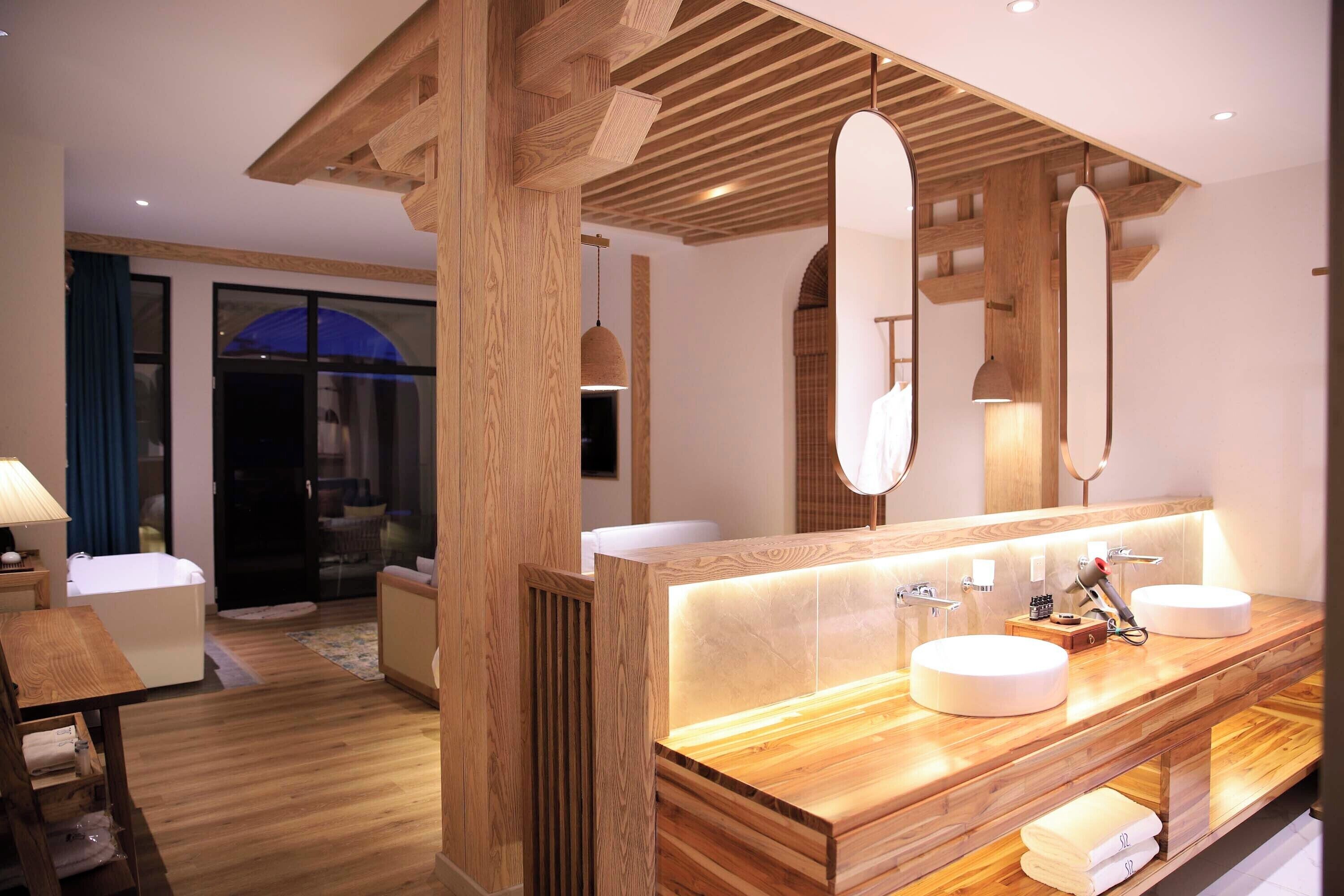A modern bathroom with wooden accents, a large mirror, and a wooden vanity with two sinks.
