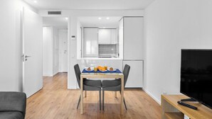 Una sala moderna con una mesa de comedor, un televisor y una zona de cocina.