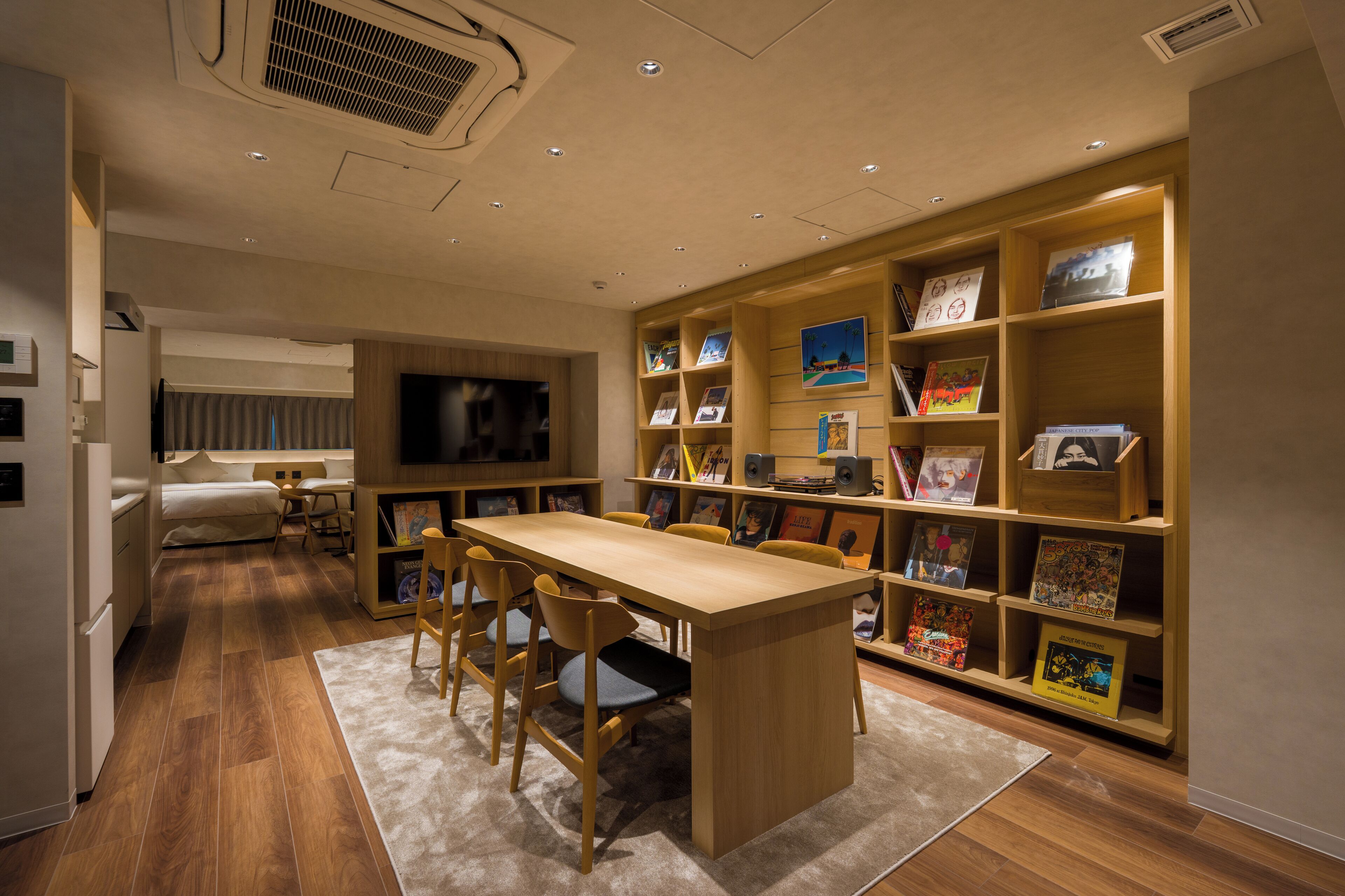 Una sala de estar moderna con una mesa de comedor de madera, sillas, un sofá y una estantería llena de libros y fotografías enmarcadas.