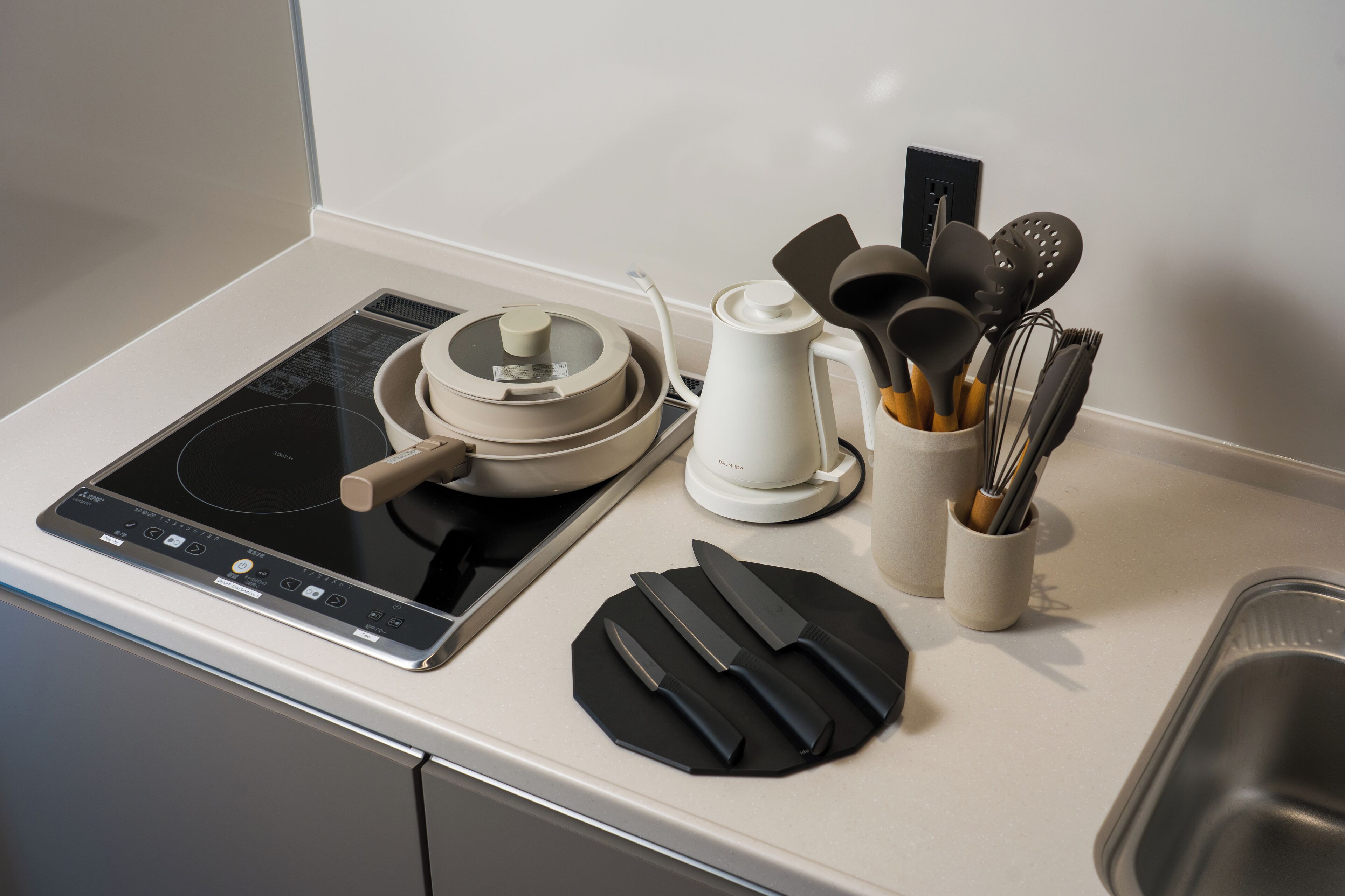 Una encimera de cocina con estufa, cafetera, hervidor y un juego de cuchillos.
