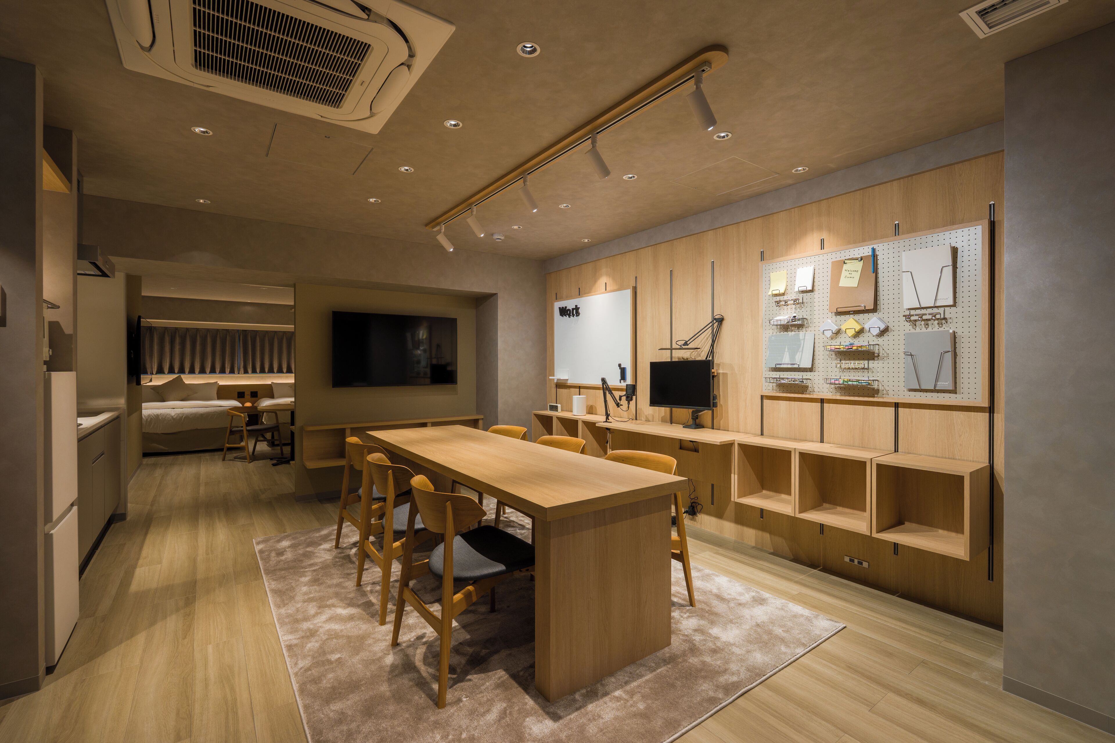 A modern kitchen with wooden cabinets, a dining area with a large table and chairs, and a built-in TV.