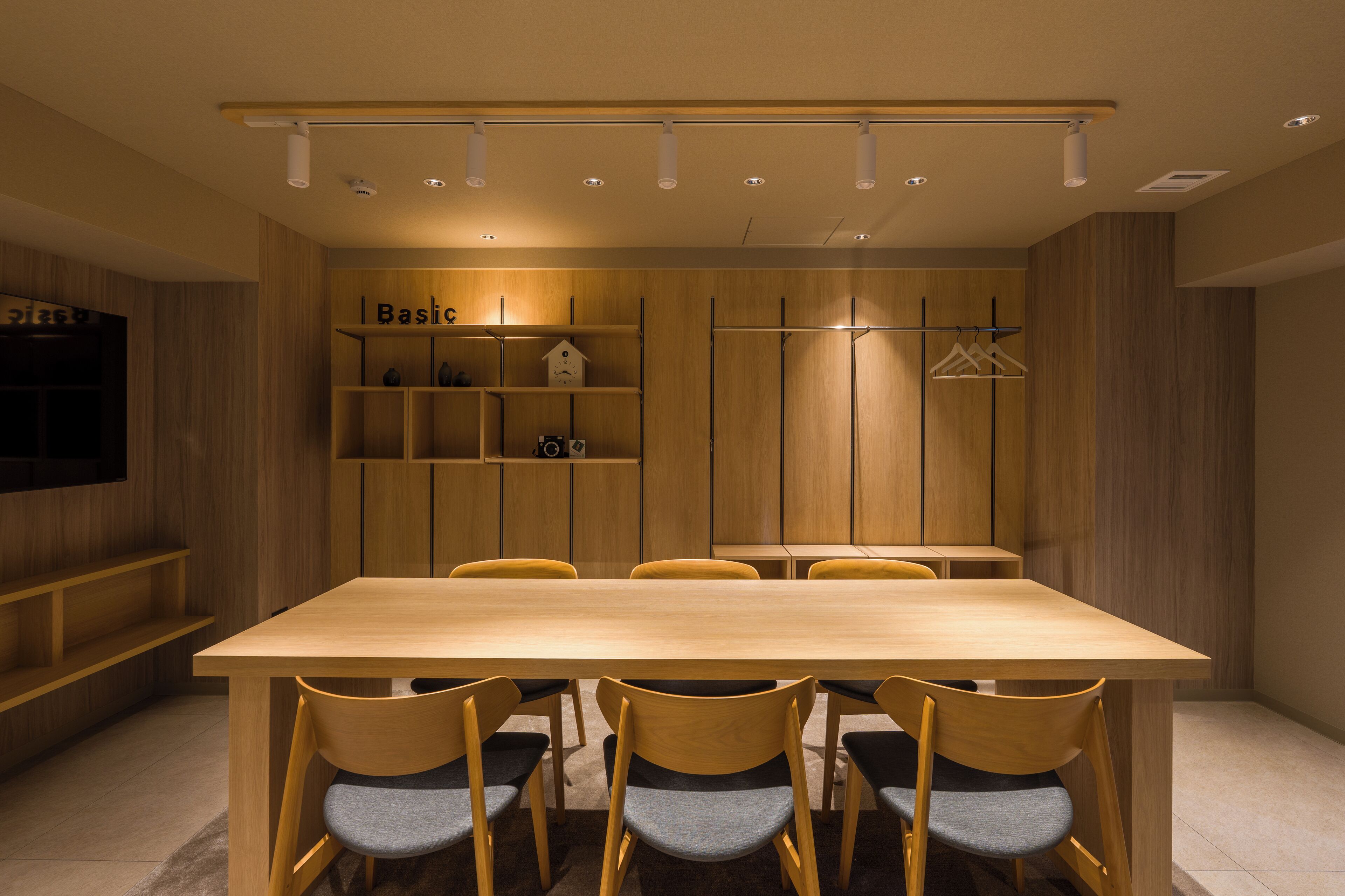 A modern dining area with a wooden table and chairs, a television, and a shelf with a house-shaped decoration.