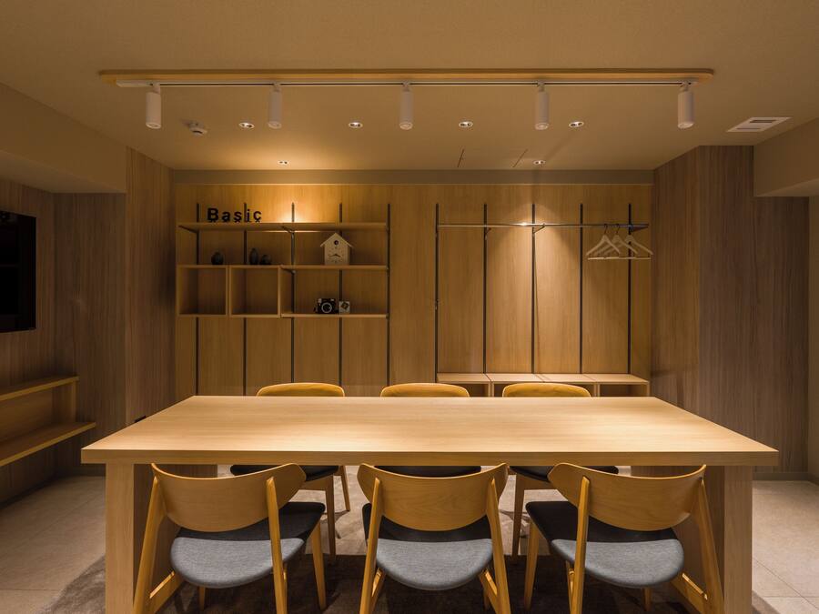 A modern dining area with a wooden table and chairs, a television, and a shelf with a house-shaped decoration.