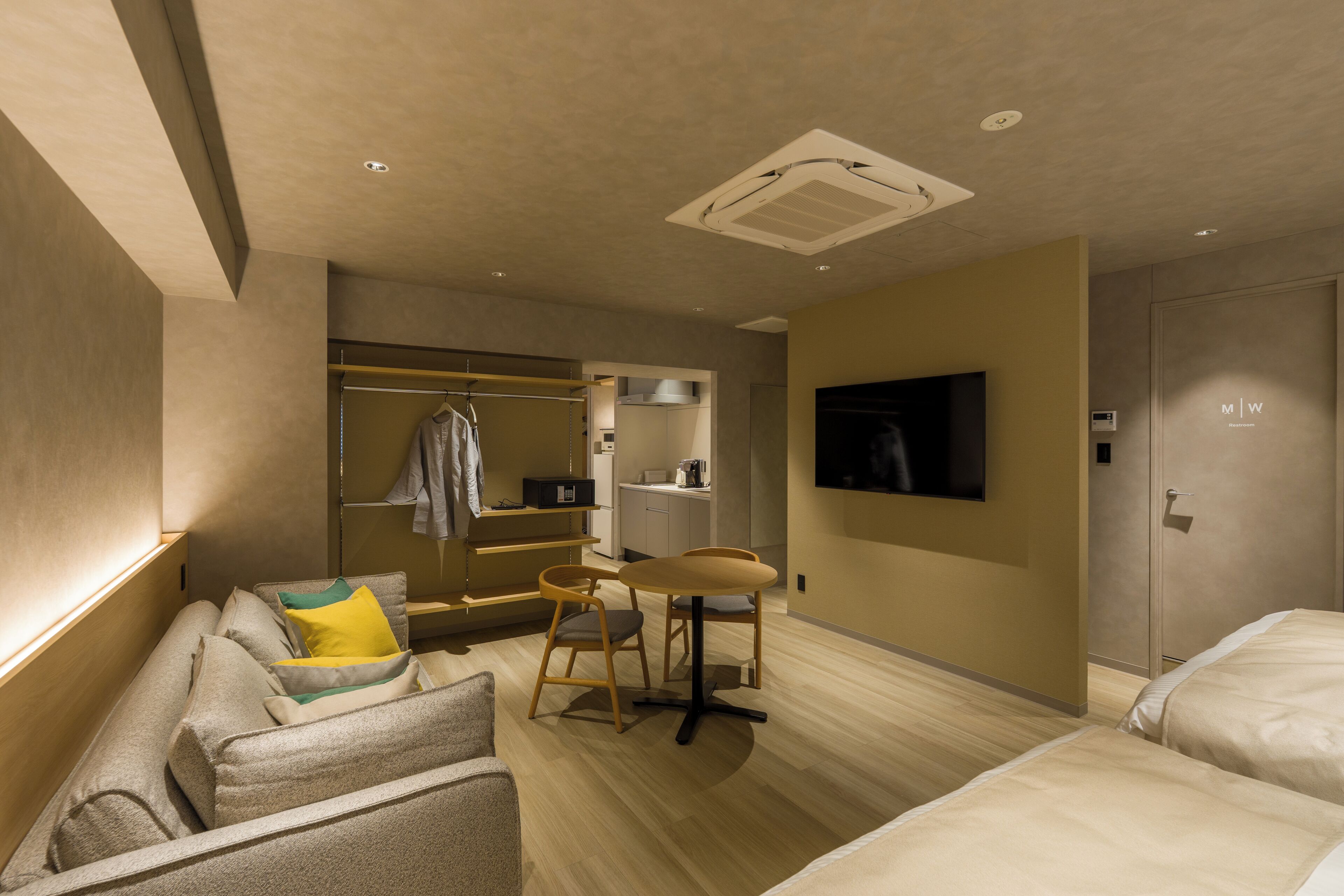 A hotel room with a sofa, a small table, a TV, a closet, and a bed.