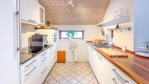 A modern kitchen with white cabinets, a wooden countertop, and a window with a plant. - Awesome apartment in Væggerløse with WiFi (Væggerløse)