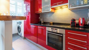 A modern kitchen with red cabinetry, stainless steel appliances, and a built-in oven. - 1-Br Apartment in Cannes, Peaceful, Seaside Atmosphere (Cannes)