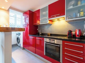 A modern kitchen with red cabinetry, stainless steel appliances, and a built-in oven. - 1-Br Apartment in Cannes, Peaceful, Seaside Atmosphere (Cannes)