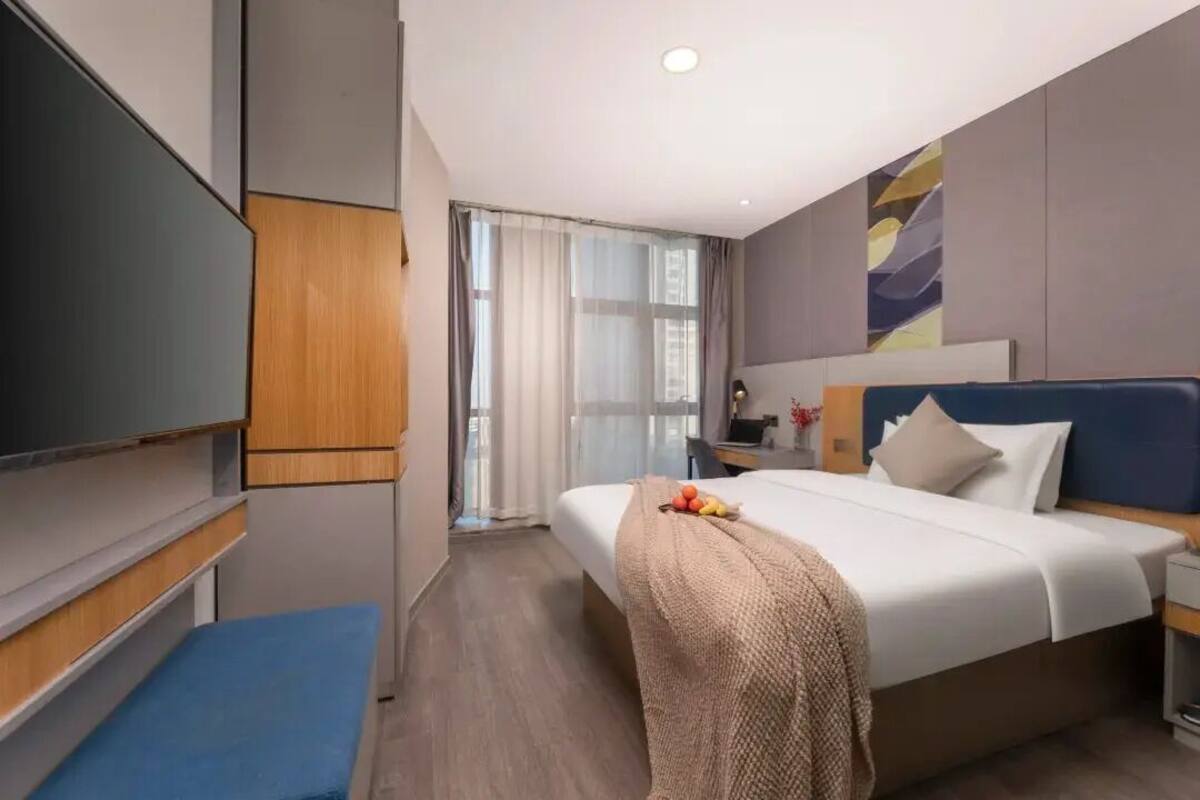 Una camera d'albergo moderna con un letto grande, una scrivania, una TV e vista all'esterno.