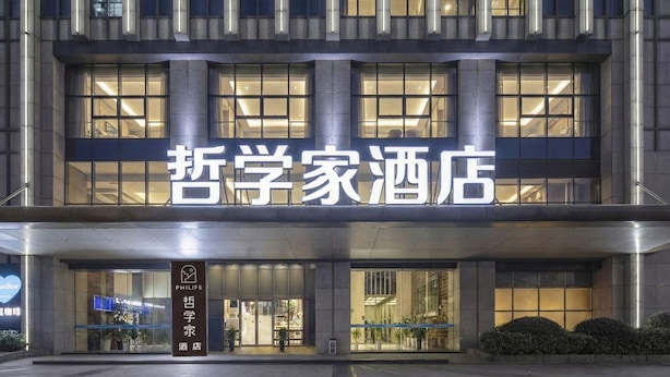 A hotel entrance with a large illuminated sign, a reception desk, and a clear pathway leading to the entrance. - suzhouzhexujiajiudian (Suzhou)