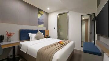 Una habitación de hotel moderna con cama, mesita de noche, televisión y espejo.