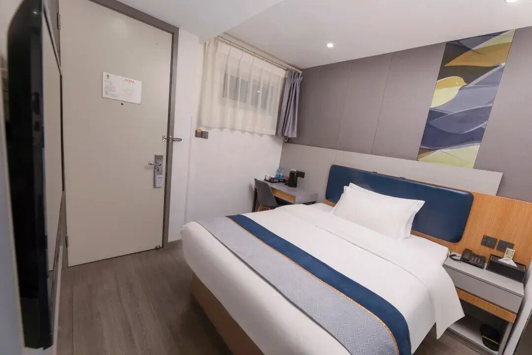 A hotel room with a bed, bedside table, and a nightstand.