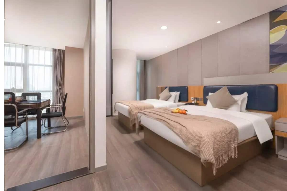 Una camera d'albergo con un letto grande, una scrivania con una sedia e una finestra con tende.