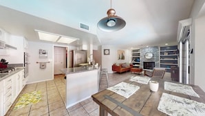 A spacious kitchen with a central island, a dining area with a wooden table, and a living room with a fireplace. - A -LV HOME PALM D (Las Vegas)