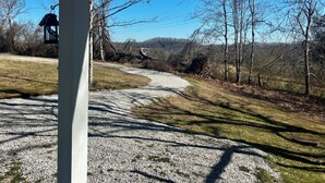 A gravel path leading through a rural landscape with trees and a clear blue sky. - Quiet, Private Home in Kingston Springs for Two (Kingston Springs)