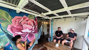 A room with a large floral mural, a hammock, wooden furniture, and a ceiling with exposed beams. - The Bocas Corner Hostel (Bocas del Toro)
