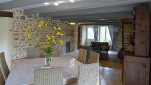 Ein Essbereich mit einer Steinwand, einem Tisch mit Stühlen und einer Vase mit gelben Blumen.