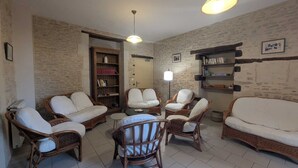 Un salon chaleureux avec des meubles en osier, une bibliothèque et une lampe.