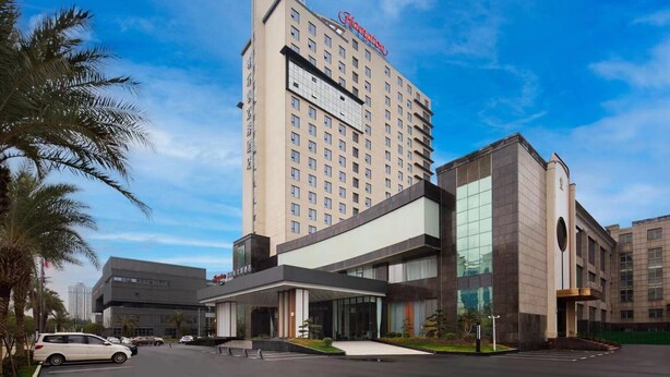 A hotel with a prominent tower and a modern building with large windows.