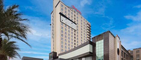 Un hotel con una torre destacada y un edificio moderno con ventanas amplias.