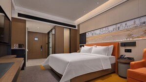A hotel room with a bed, a desk, a chair, and a painting on the wall.