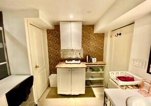 A compact kitchen with white cabinets, a small countertop, and a microwave. There is a white door on the left and a white cabinet on the right. - Enjoyable 1-bedroom house with AC in Richmond Hill (Richmond Hill)