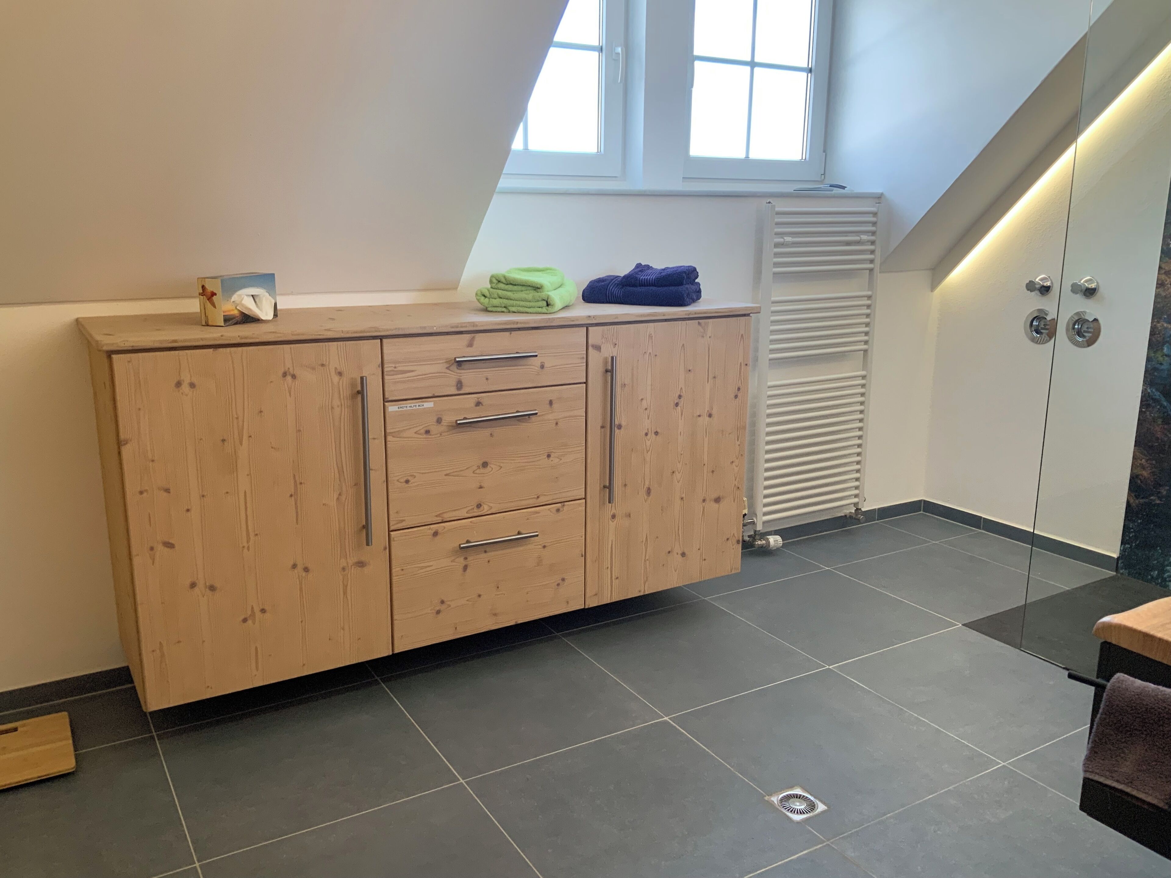 A modern kitchen with a wooden cabinet, a window, and a radiator.