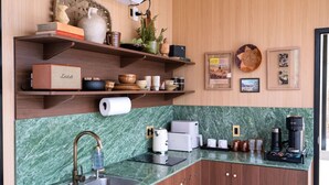 Cuina moderna amb taulell de marbre, prestatges integrats i diversos electrodomèstics.