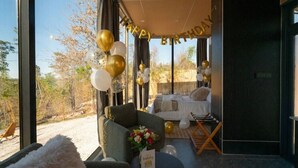 A room with a view of the outdoors, a bed, a chair, and a table with a birthday card.