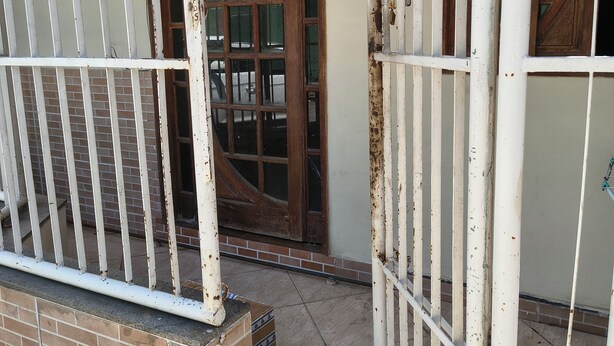 A gated entrance with a wooden door and a number '23' on the wall.