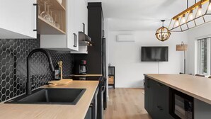 A modern kitchen with a black and white backsplash, a wooden countertop, and a black range hood.